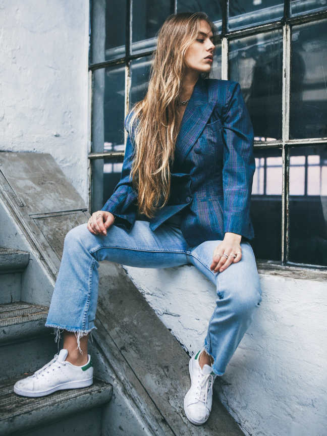 mergina su melynu svarku ir dzinsais sedinti ant laiptu